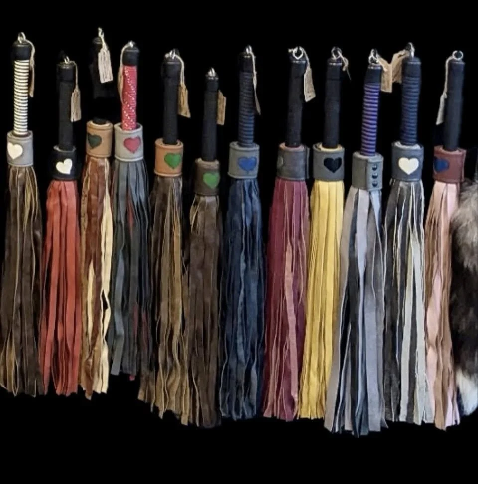 Collection of handmade tassels with striped fabric and decorative tops in various colors, arranged in a row.