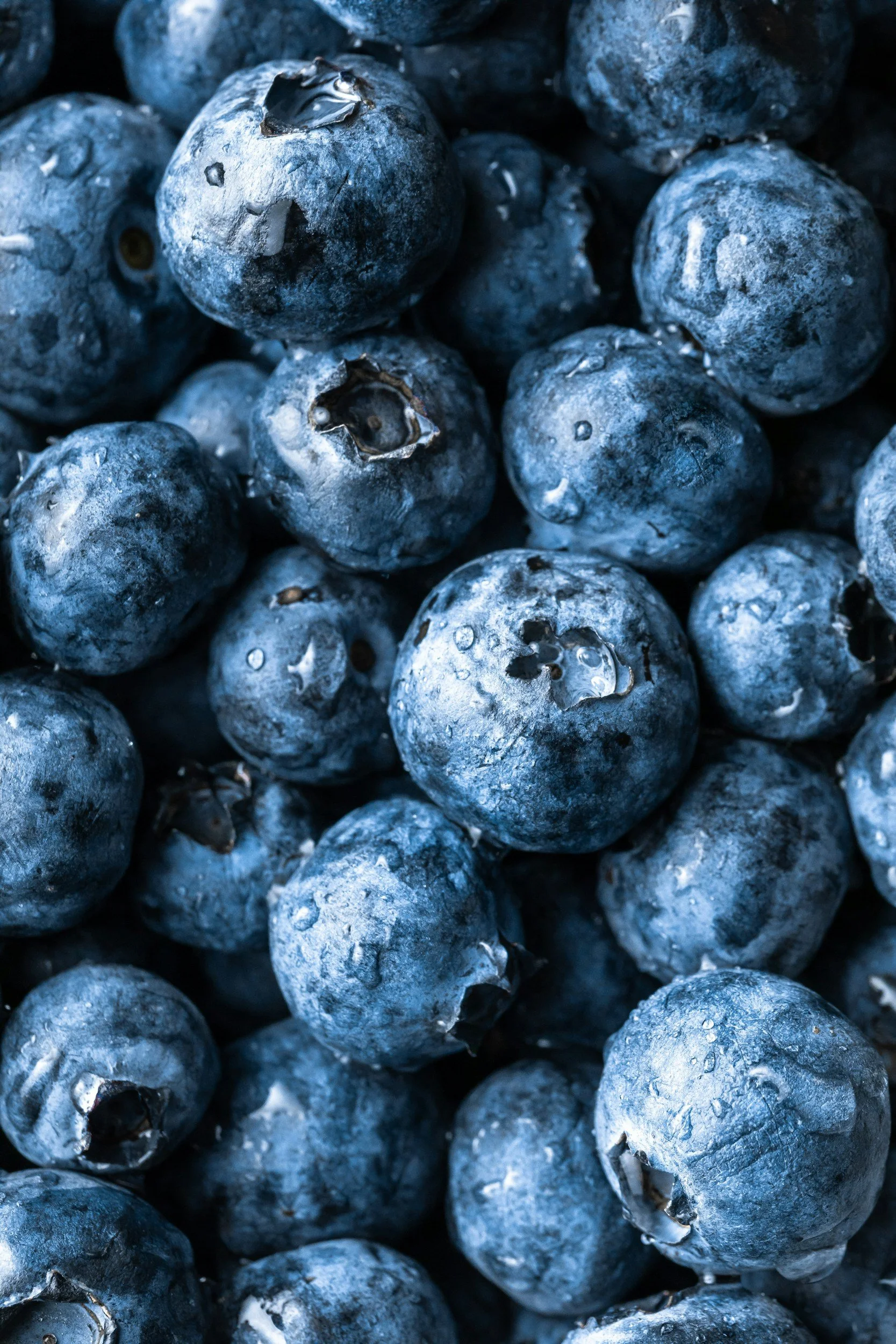 Close-up of fresh blueberries with some water droplets on their surfaces.