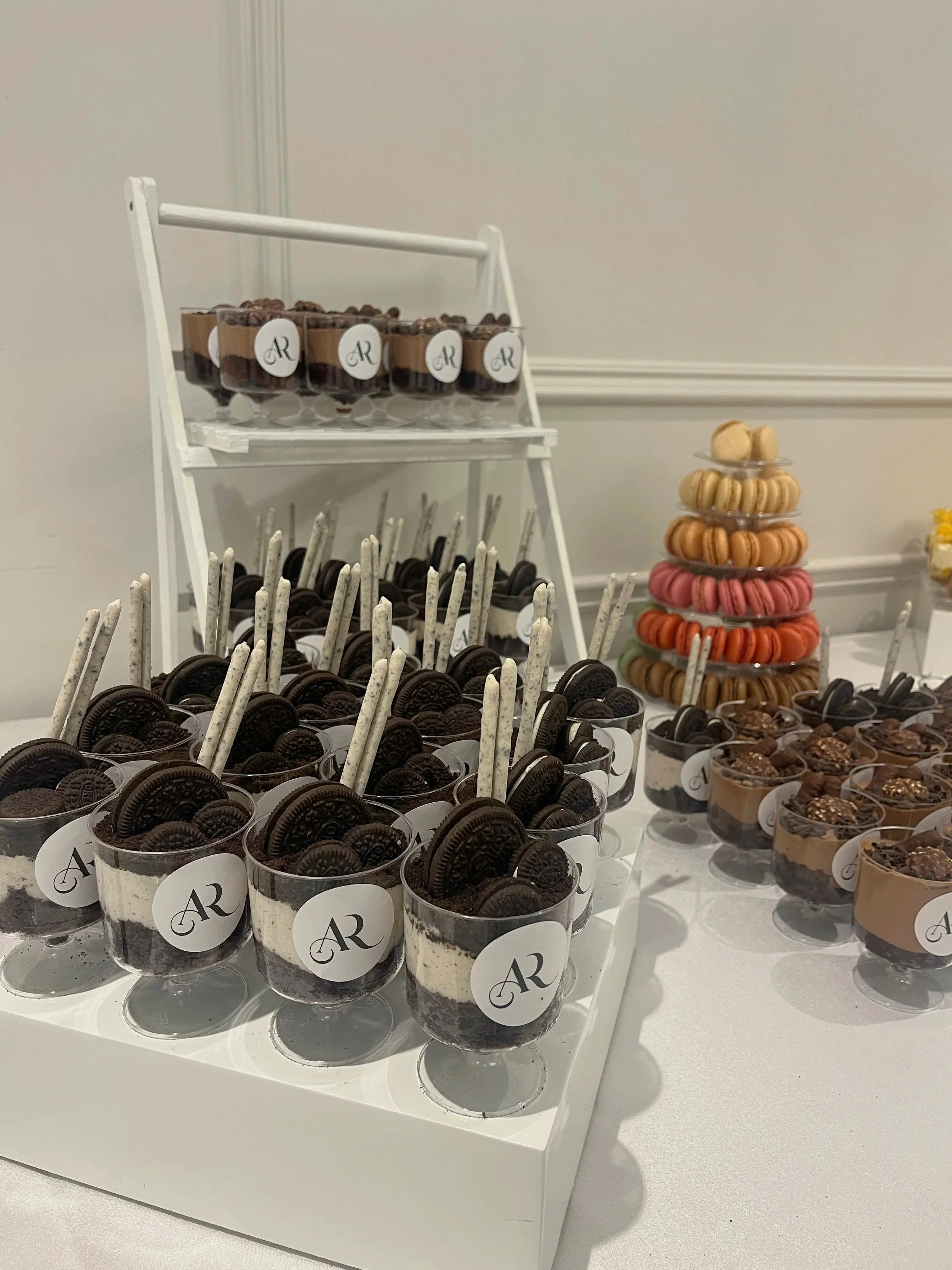 Dessert table with Oreo parfaits, macarons, and chocolate desserts.