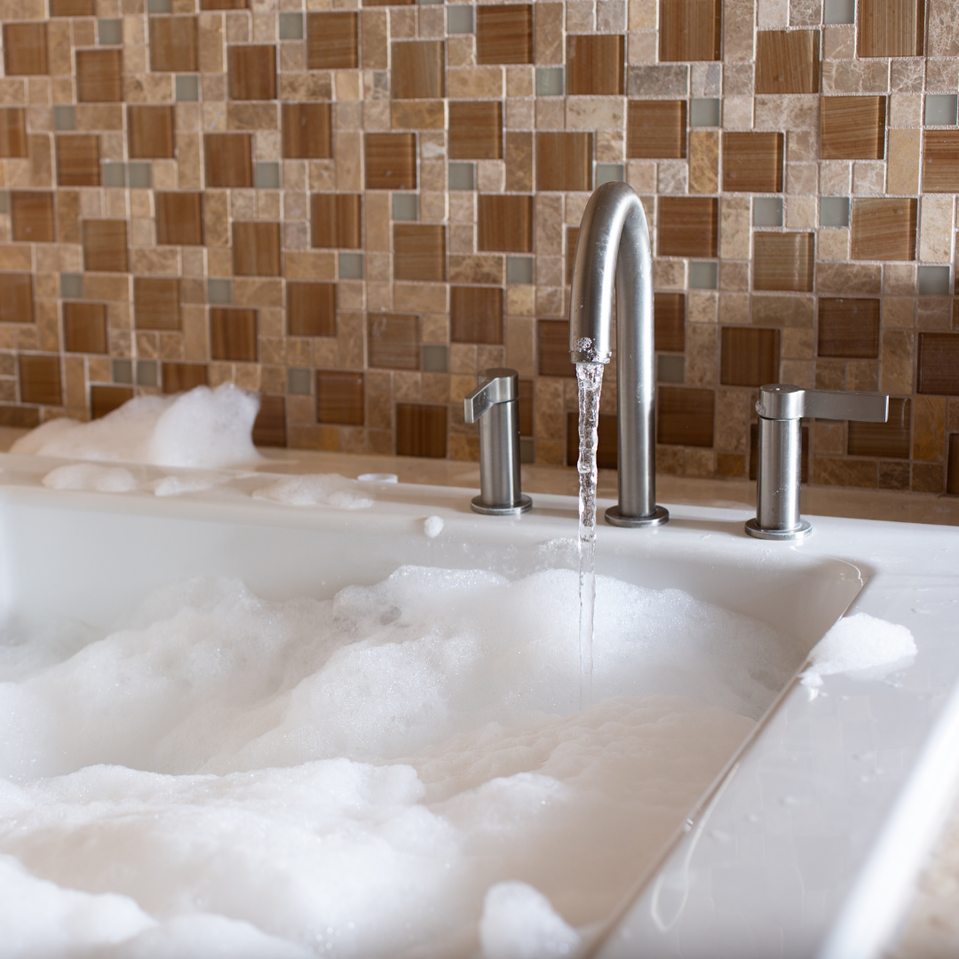 Bathtub filled with hot water and running tap