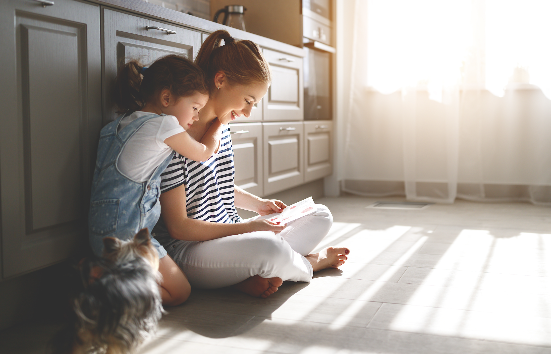 Mother and child sitting on the kitchen floor in a warm home heated by gas ducted heating in Central Victoria.