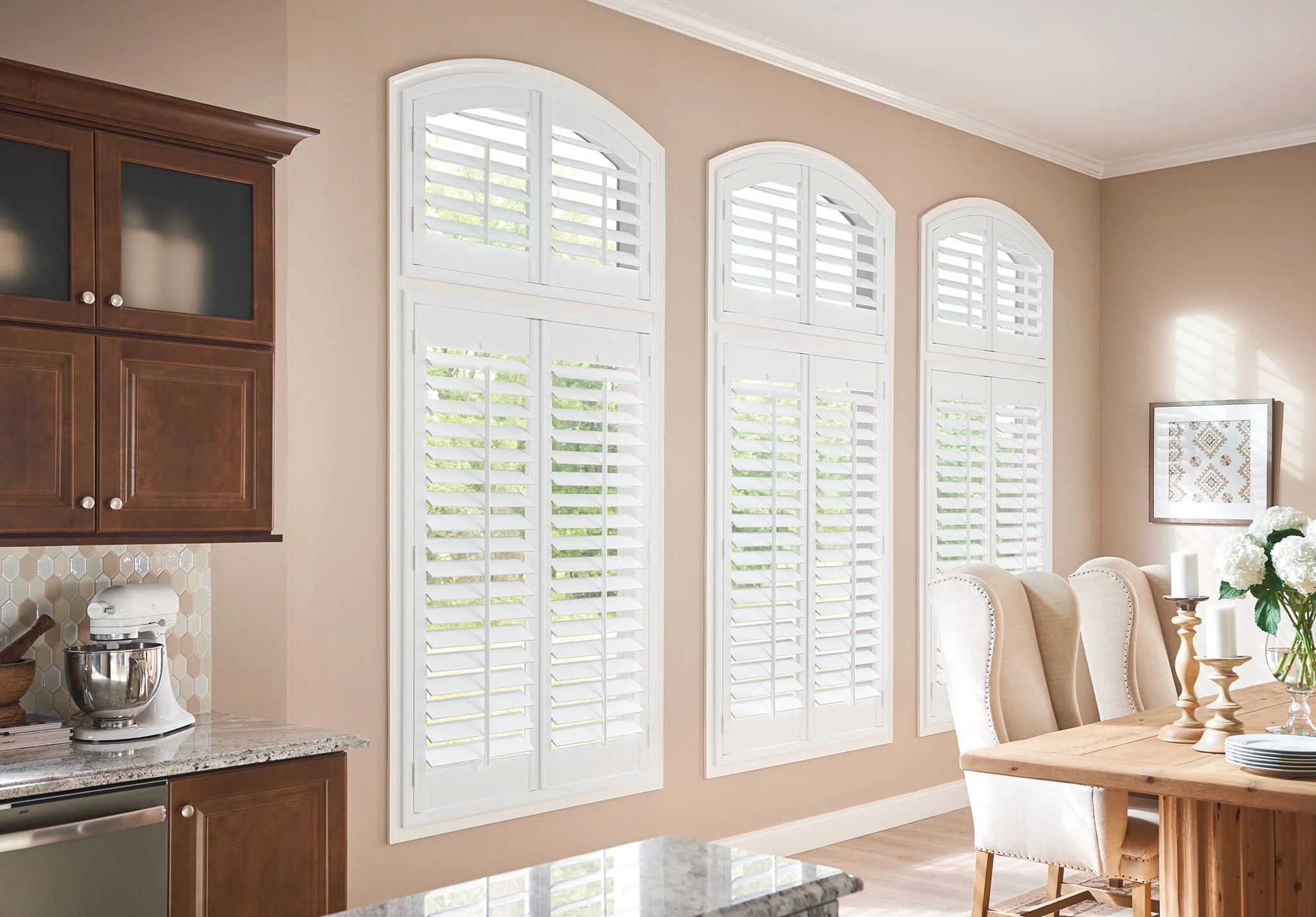 A close-up of white horizontal window blinds partially open, allowing sunlight to stream into a room and revealing a view of a construction site outside through the clear glass window.