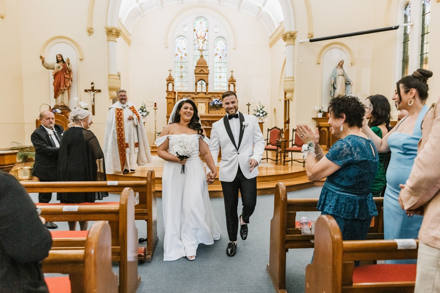Modern wooden house with large glass window set against a mountain landscape with dry grass and sparse trees.