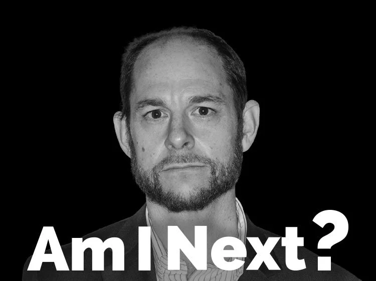 Black-and-white portrait of a man with dark hair and beard, wearing a suit, with text 'Am I Next?' at the bottom.