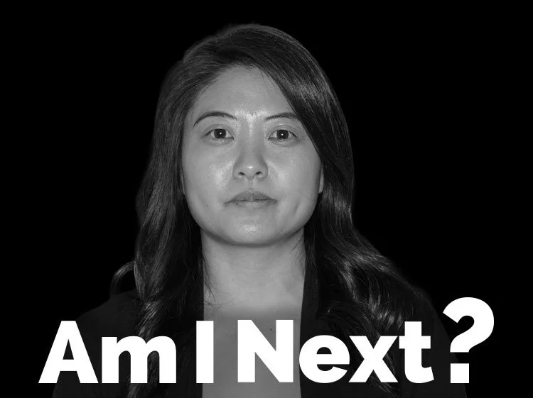 Black and white portrait of a woman with long dark hair, looking directly at the camera with a neutral expression, against a black background, with text below reading "Am I Next?"