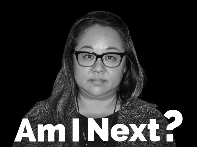 Black and white photo of a woman with glasses, long hair, and a serious expression, with the text "Am I Next?" at the bottom.