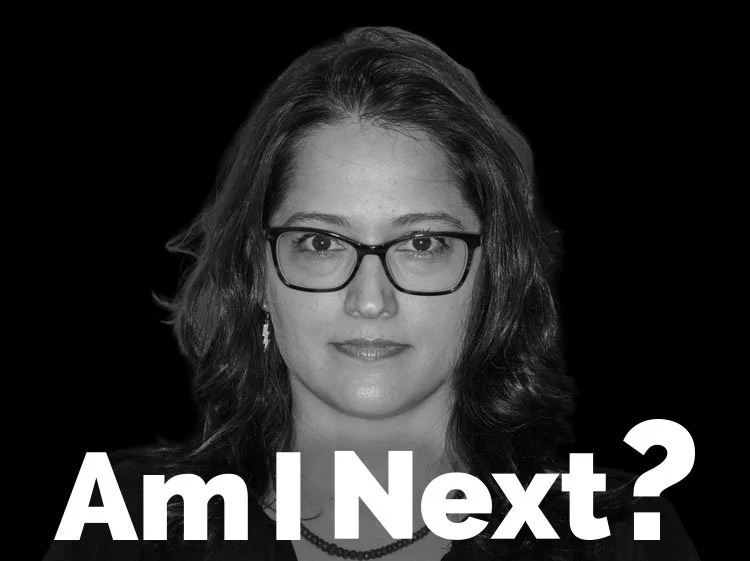 Black and white portrait of a woman with glasses and shoulder-length hair, with the text 'Am I Next?' in bold white letters at the bottom.