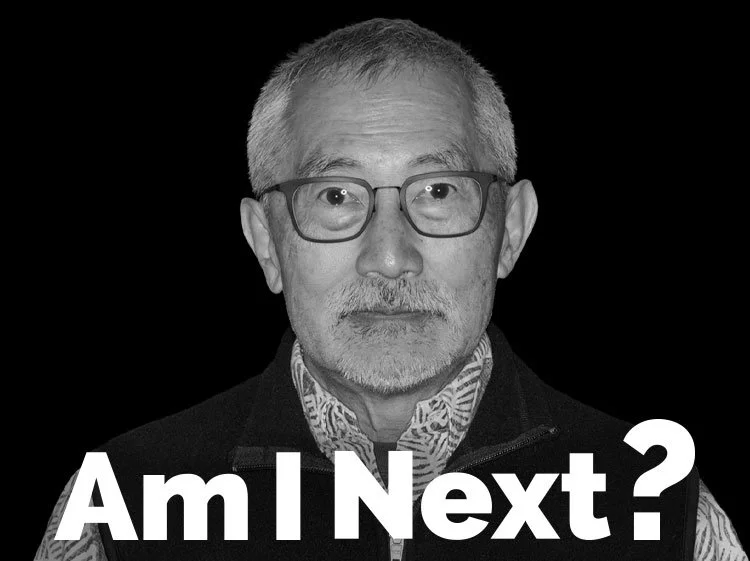 Black and white close-up of an older man with gray hair, glasses, and a beard, wearing a patterned shirt and a vest, with the text "Am I Next?" in bold white letters at the bottom.