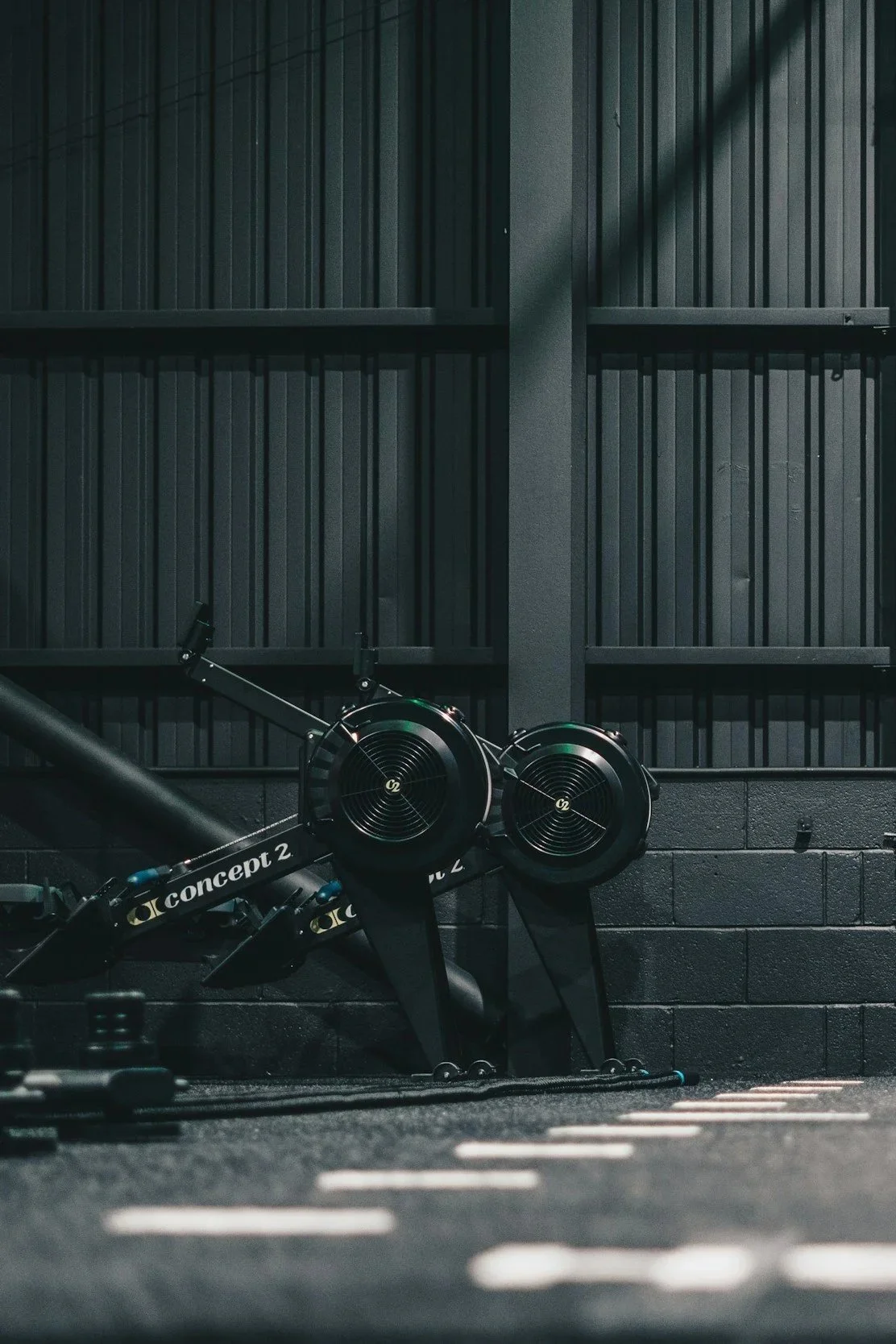 Indoor gym with a Concept 2 rowing machine against a black wall and acoustic panels.