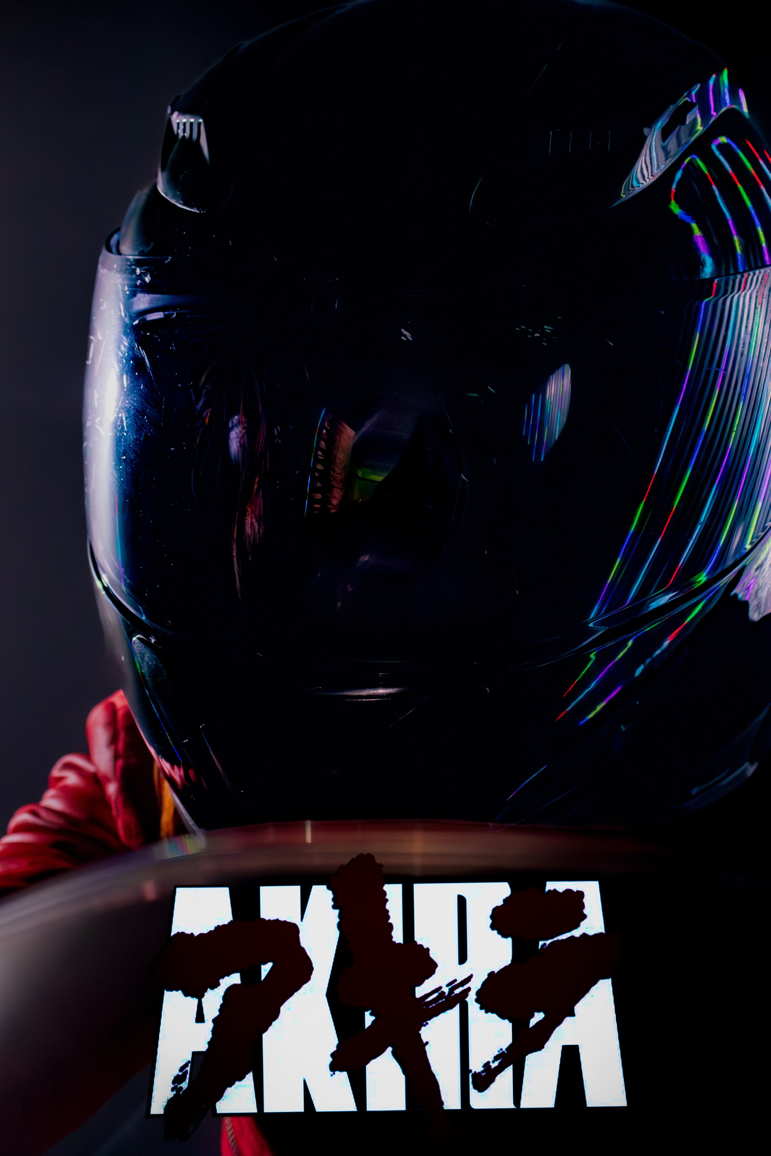 Close-up of a motorcycle helmet with a dark, reflective surface and rainbow-colored streaks, and part of a sign with bold, white text reading 'ARK' in the foreground.