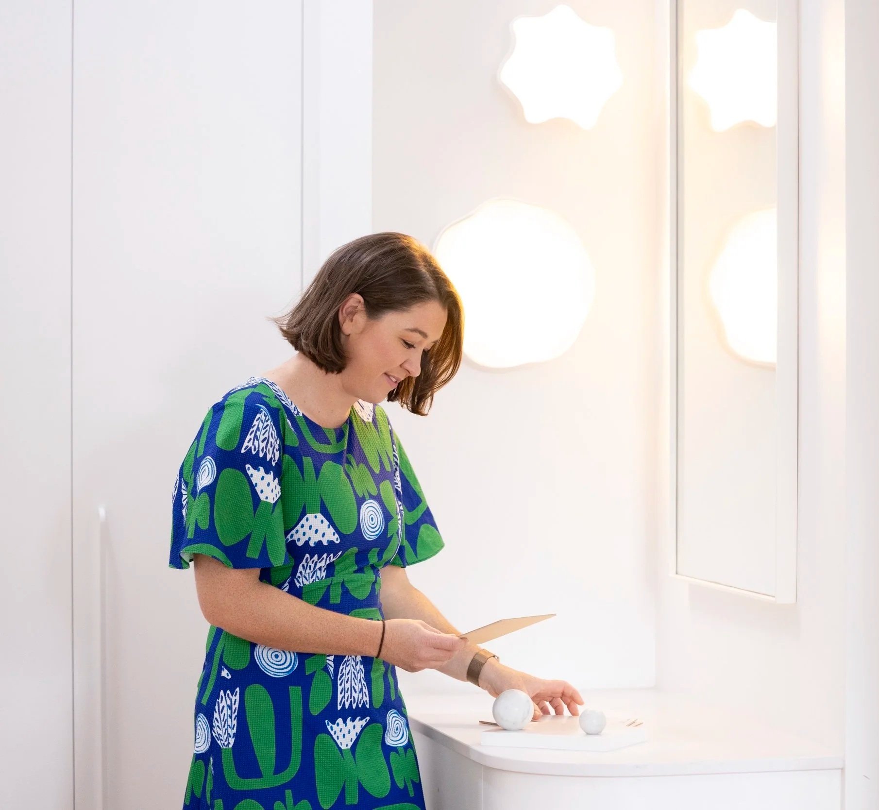 Bethany looking at interior design samples in a clean, white, simple bathroom she designed.