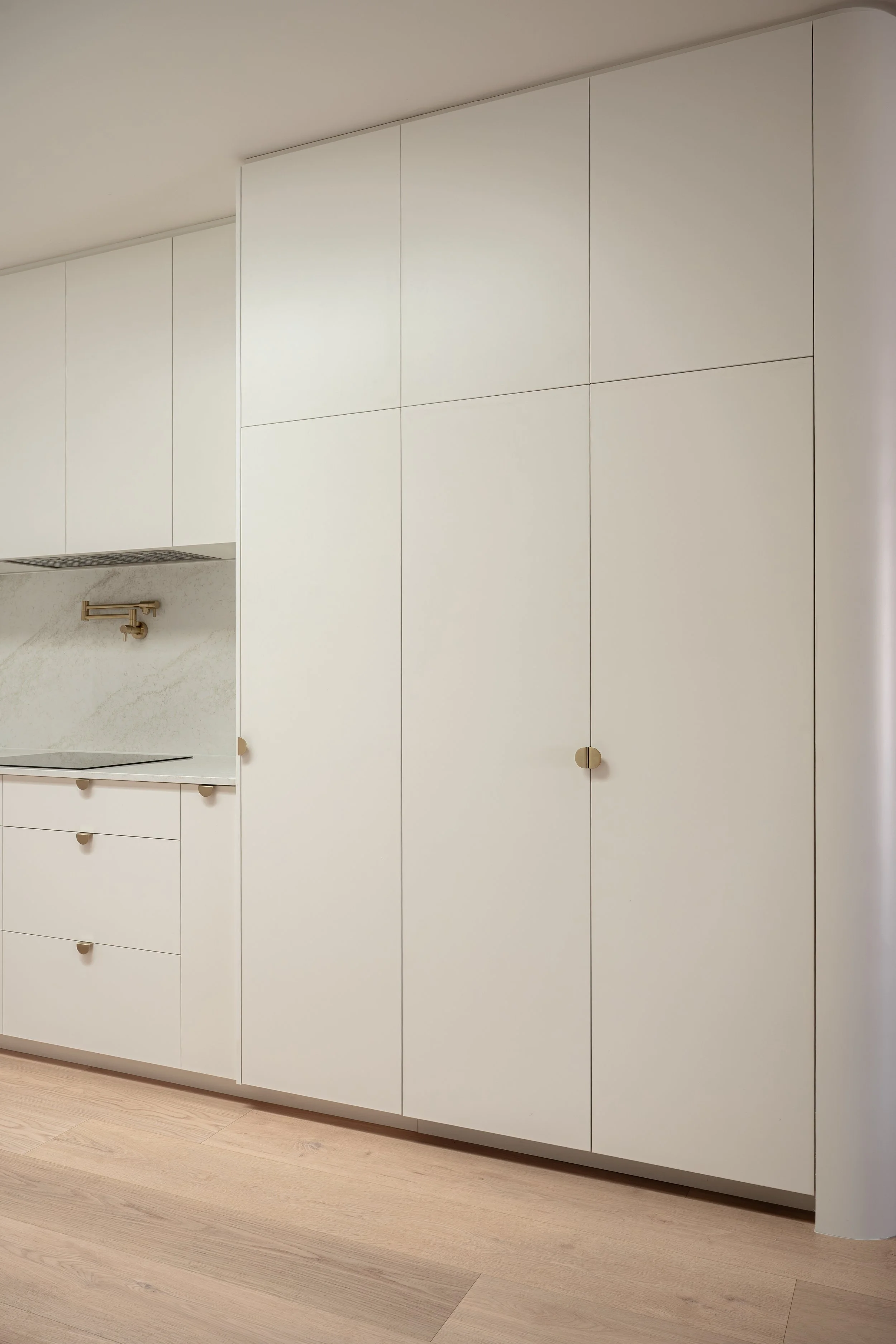 Classic white kitchen with brass handles, pot filler, and stone splashback. 