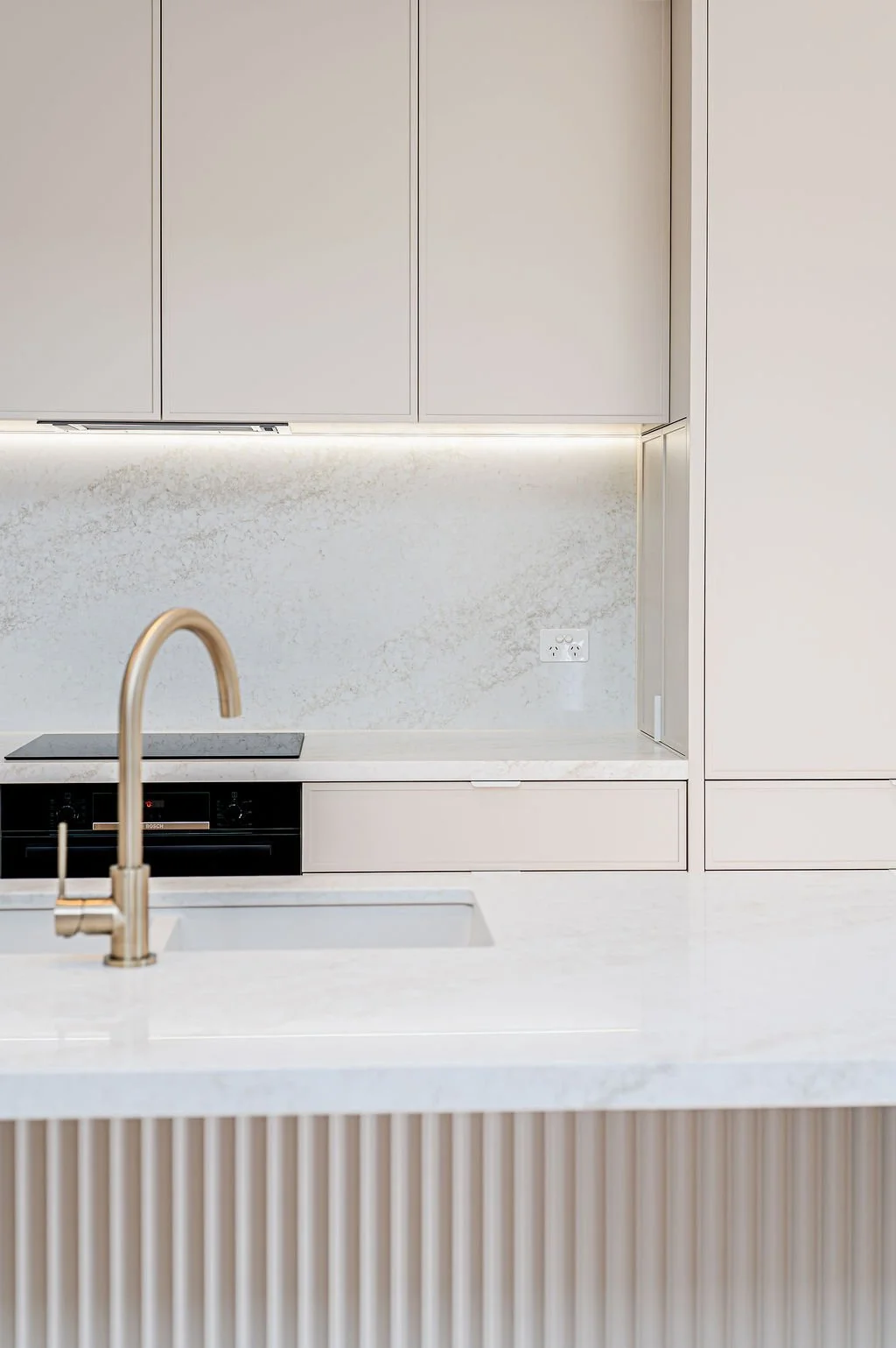 Simple white kitchen with stone benchtops.
