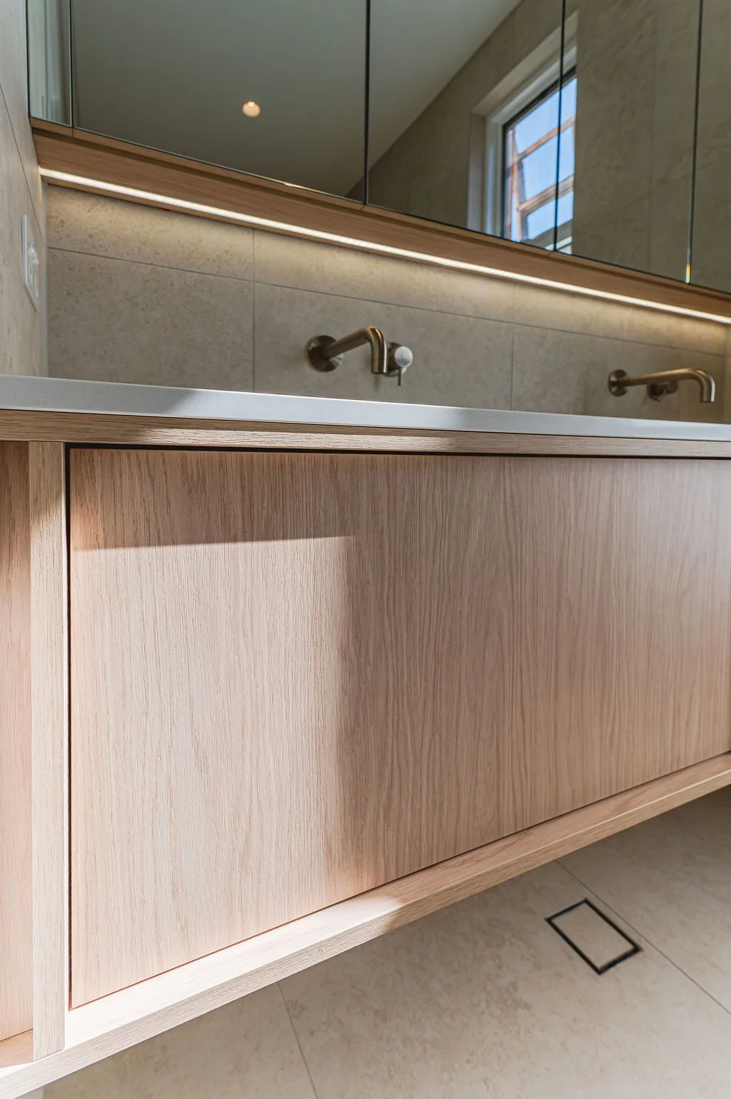 Floating timbergrain vanity with stone benchtop in a neutral bathroom