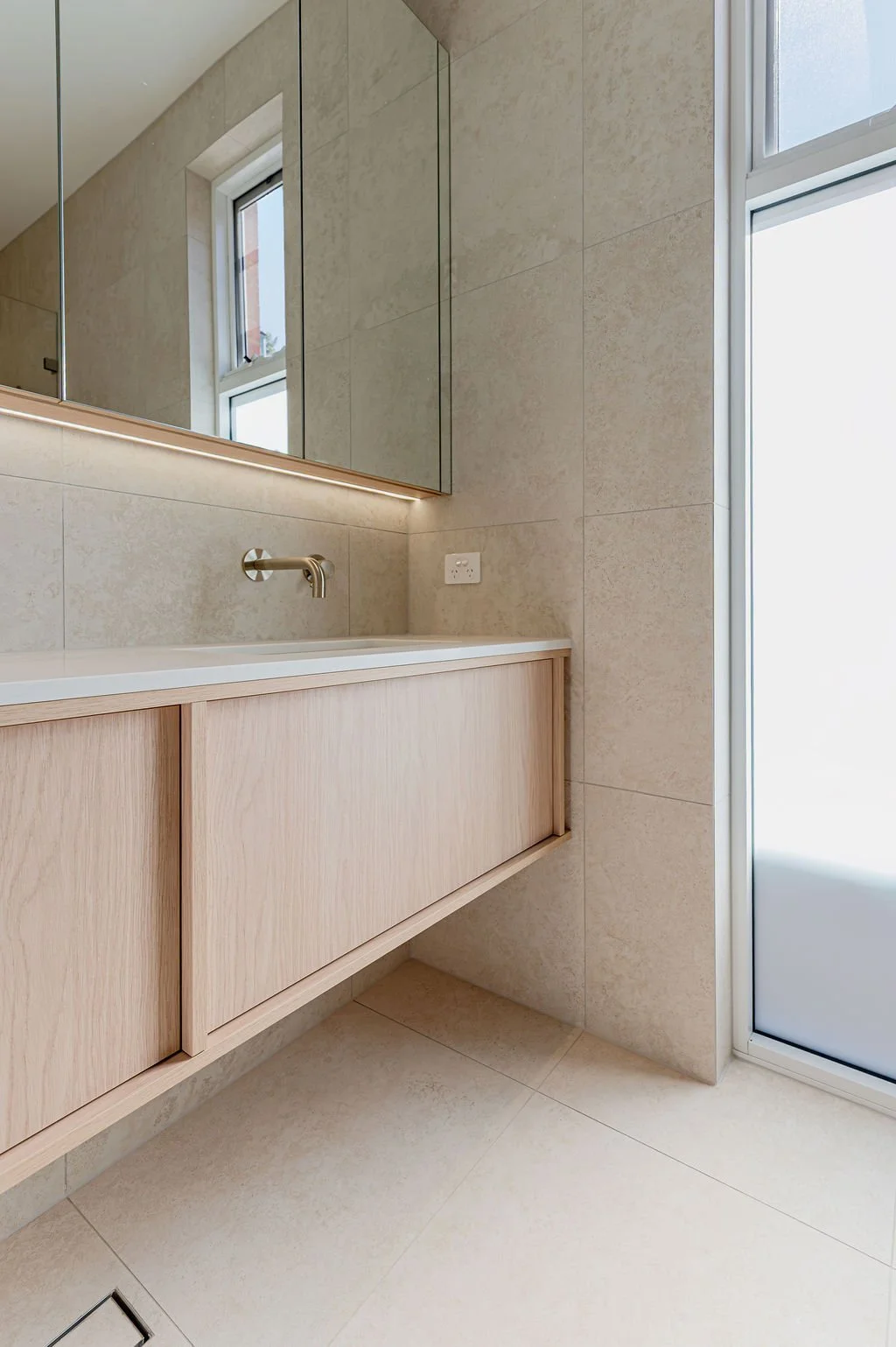 Floating timbergrain vanity with stone benchtop in a neutral bathroom