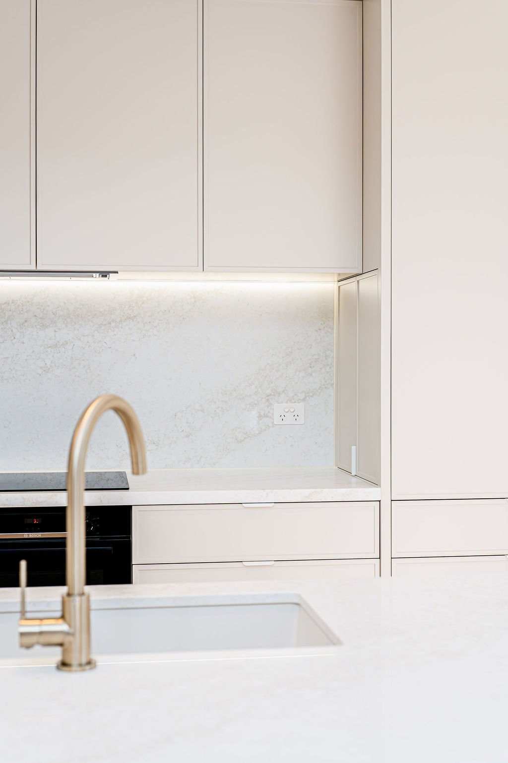 Simple white kitchen with stone benchtops.