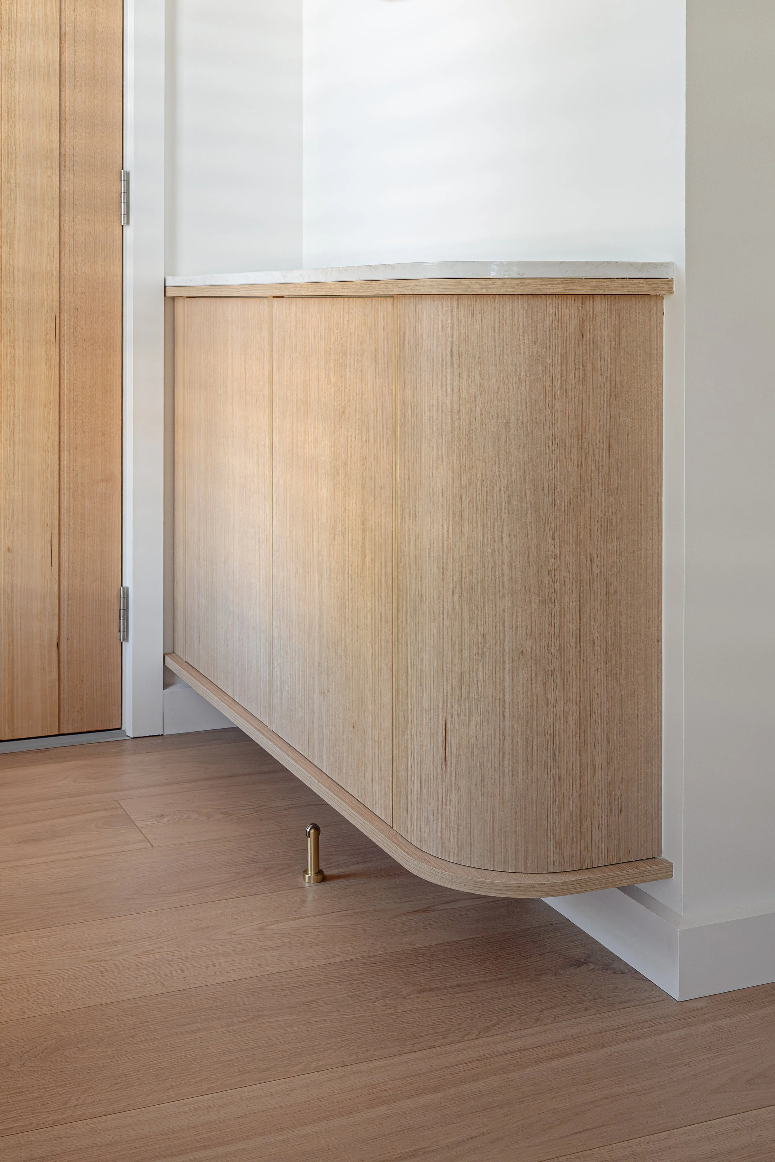 Curved timbergrain entry cabinetry with stone benchtop. 