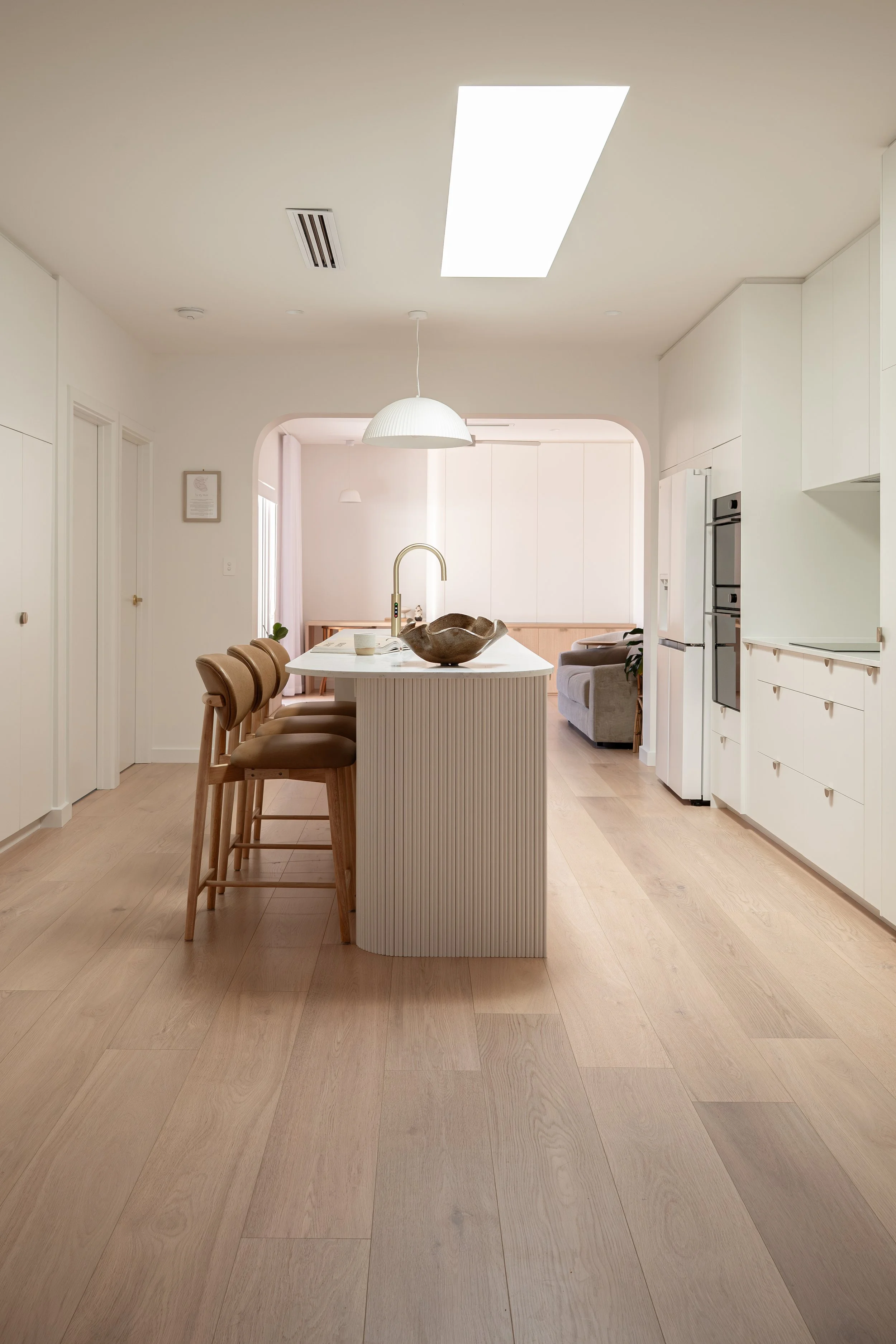 Neutral kitchen, featuring timber and feature island battoning and a curved opening. 