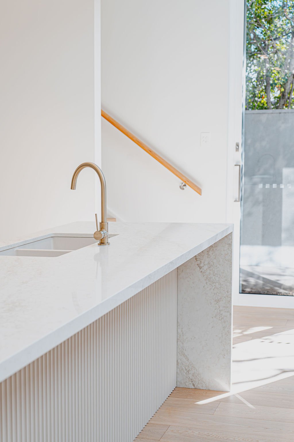 Simple white kitchen island with with and tap and stone benchtops.