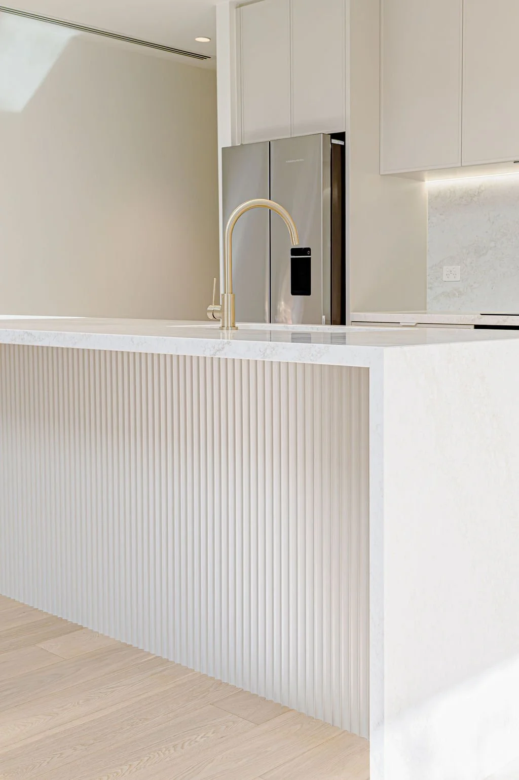 Simple white kitchen with stone benchtops and panelling to the island.