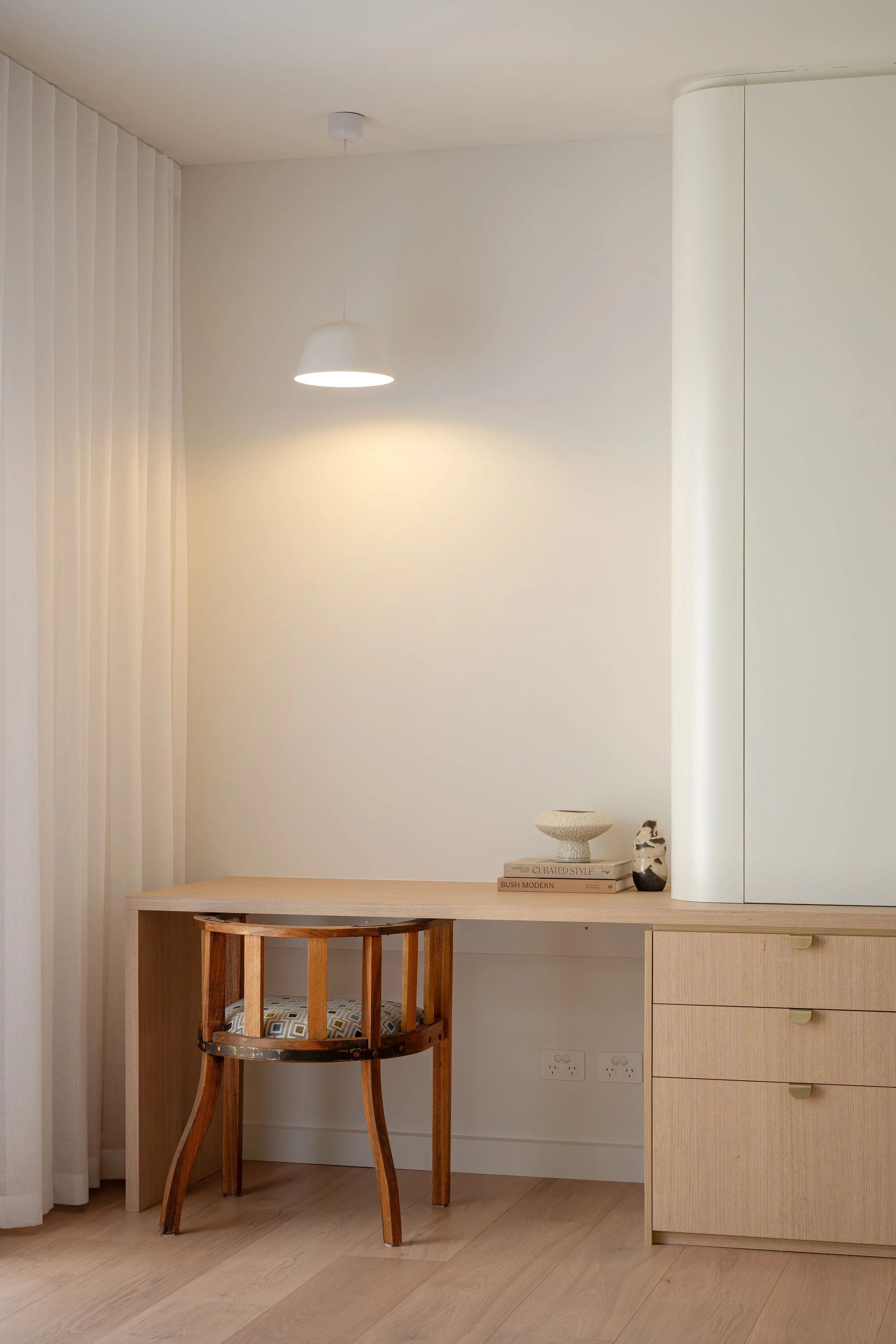 Office nook featuring timber grain cabinetry and classic white curves. 