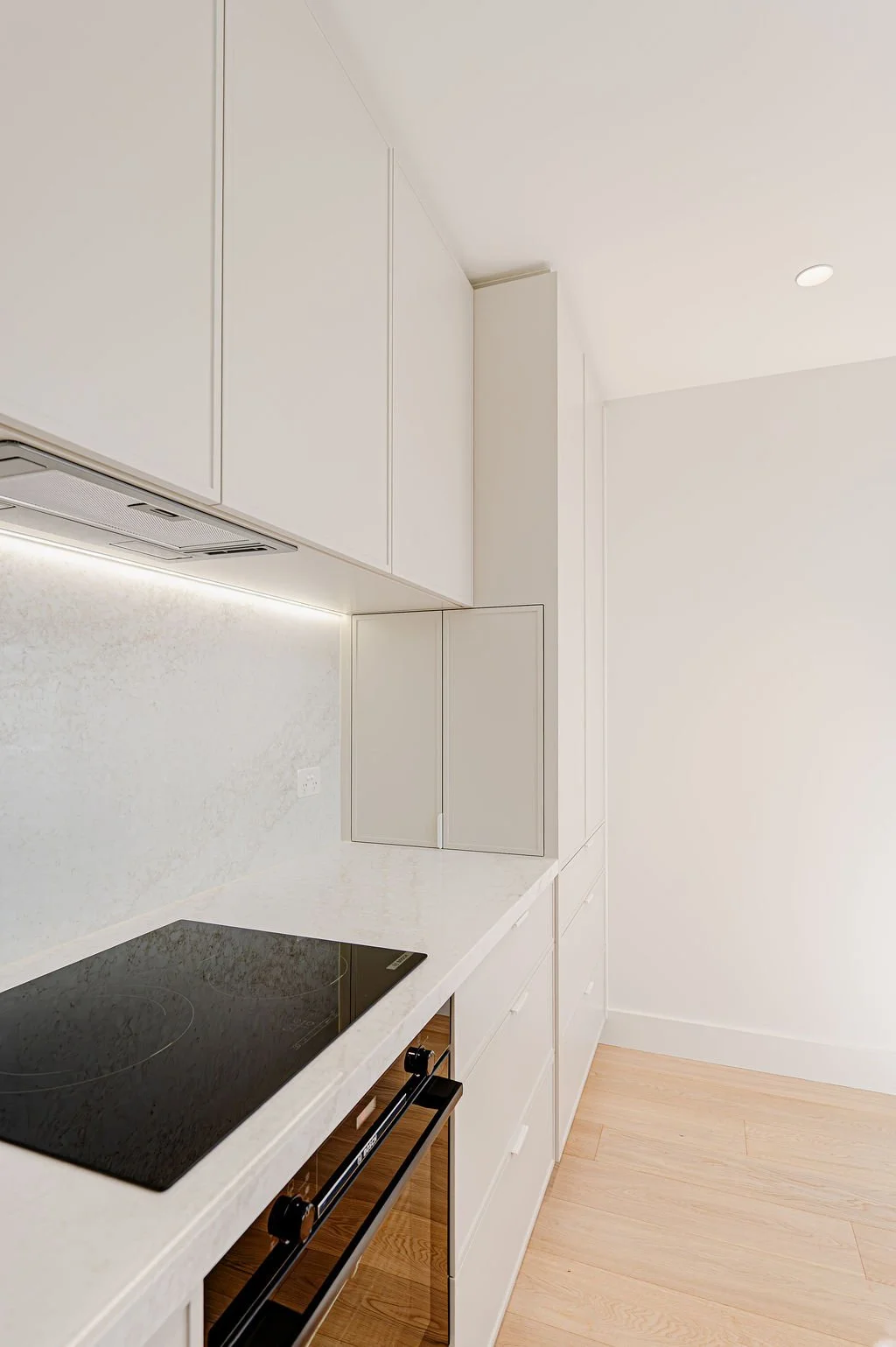 Simple white kitchen with stone benchtops.