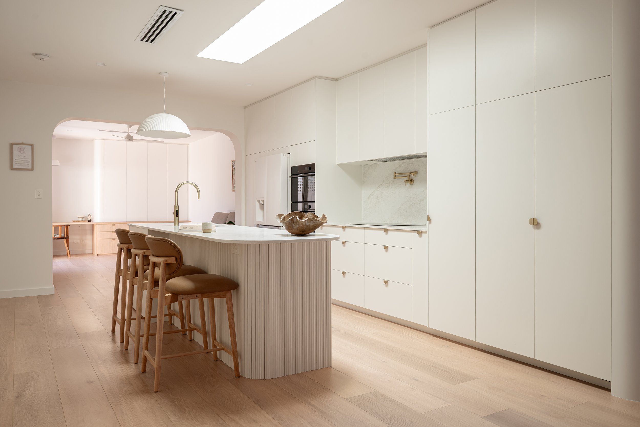 Classic white kitchen with warm timber tones and brass features. 