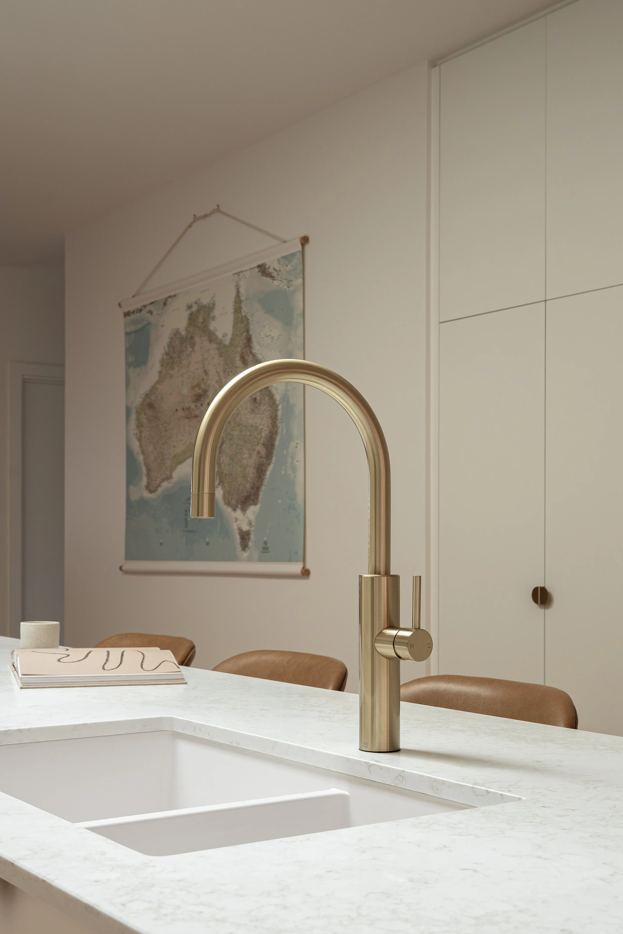 Brass gooseneck tap with white undermount sink in a stone island benchtop. 