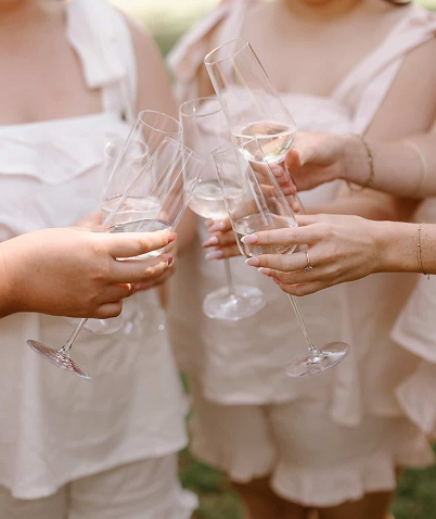 Four people toasting with champagne glasses outdoors.