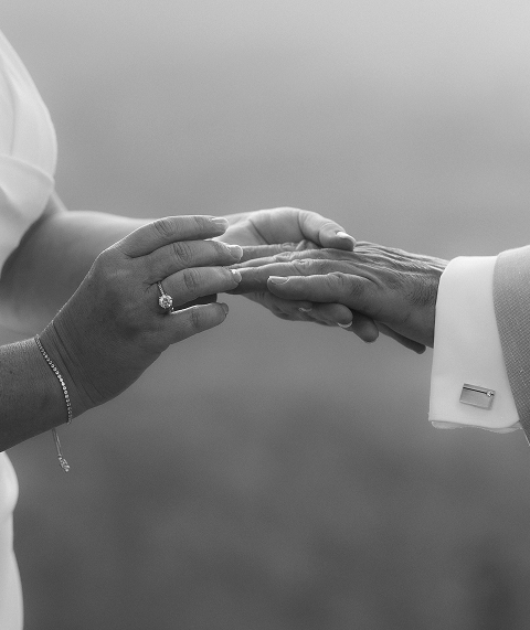 Two people holding hands, one with a ring on the ring finger, black and white photo.