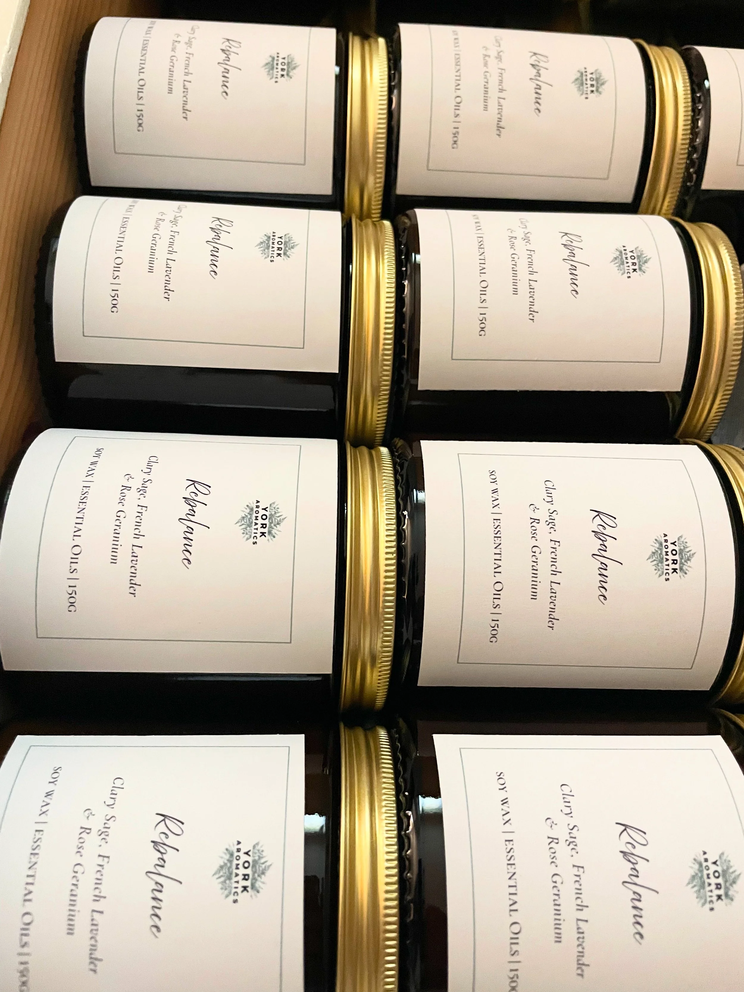 York Aromatics, Multiple jars of rosemary flavored clay soap, each with a white label and gold lid, placed in a wooden crate.