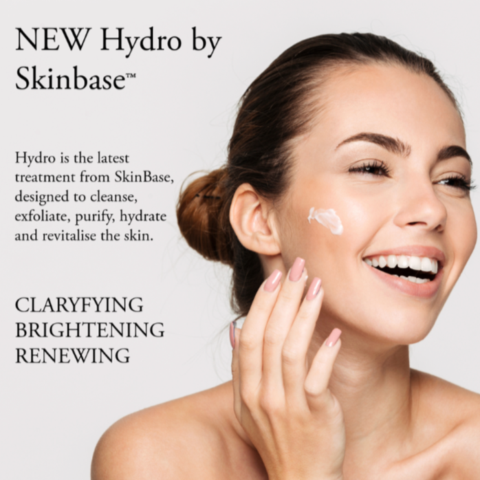 A smiling woman with fair skin and brown hair in a bun applies a dollop of cream to her cheek in a skincare product advertisement for SkinBase Hydro, emphasizing clarity, brightness, and renewal, Velvet studios ready made template