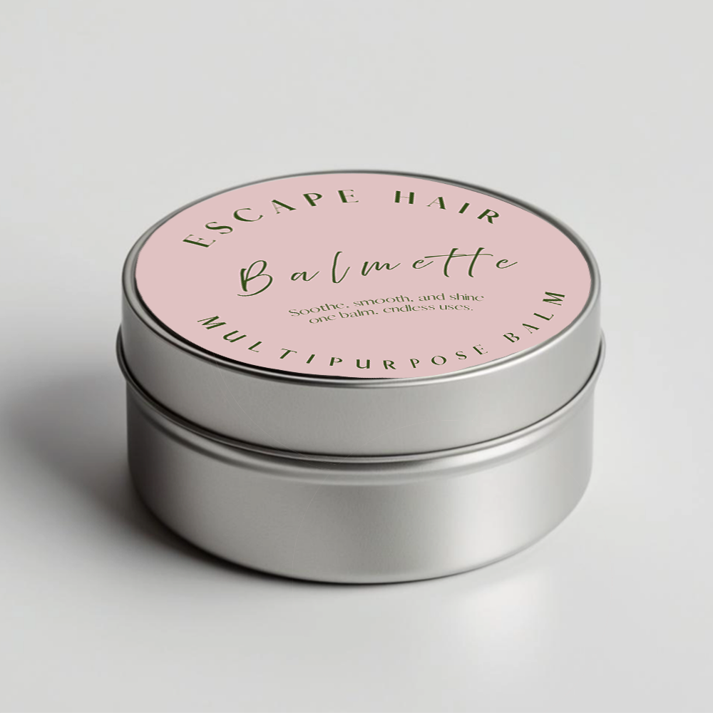 A round, metallic container with a pink label reading "Escape Hair Balmette" and text describing it as a multi-purpose balm that soothes, smooths, and shines, ending with "one balm, endless uses."