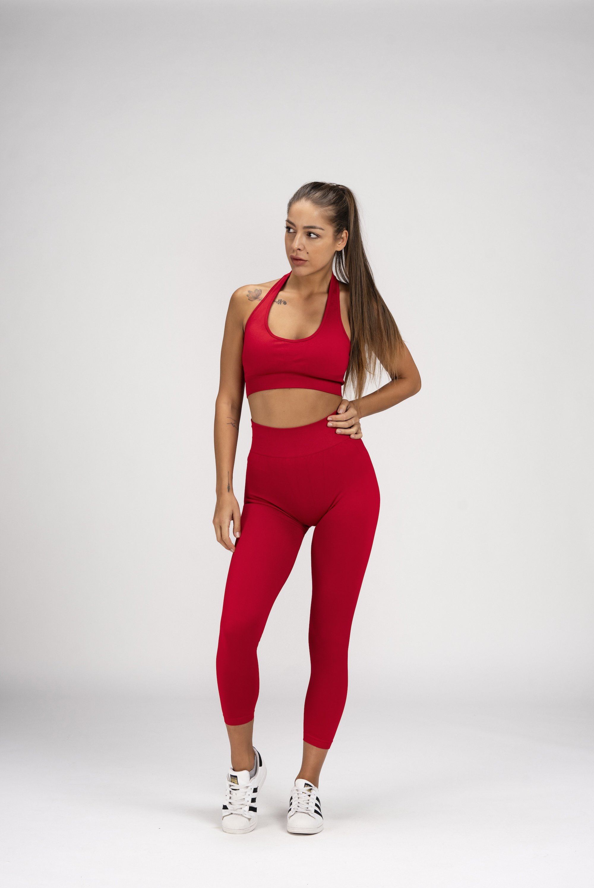 Model wearing a red Annathletics sports bra and leggings against a neutral studio background.