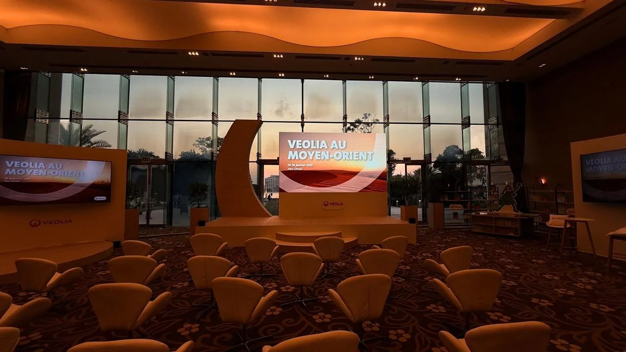 The completed venue for Veolia Au Moyen-Orient in Abu Dhabi, showing the central stage, presentation screens, branded installations and informal seating designed for the leadership meeting.