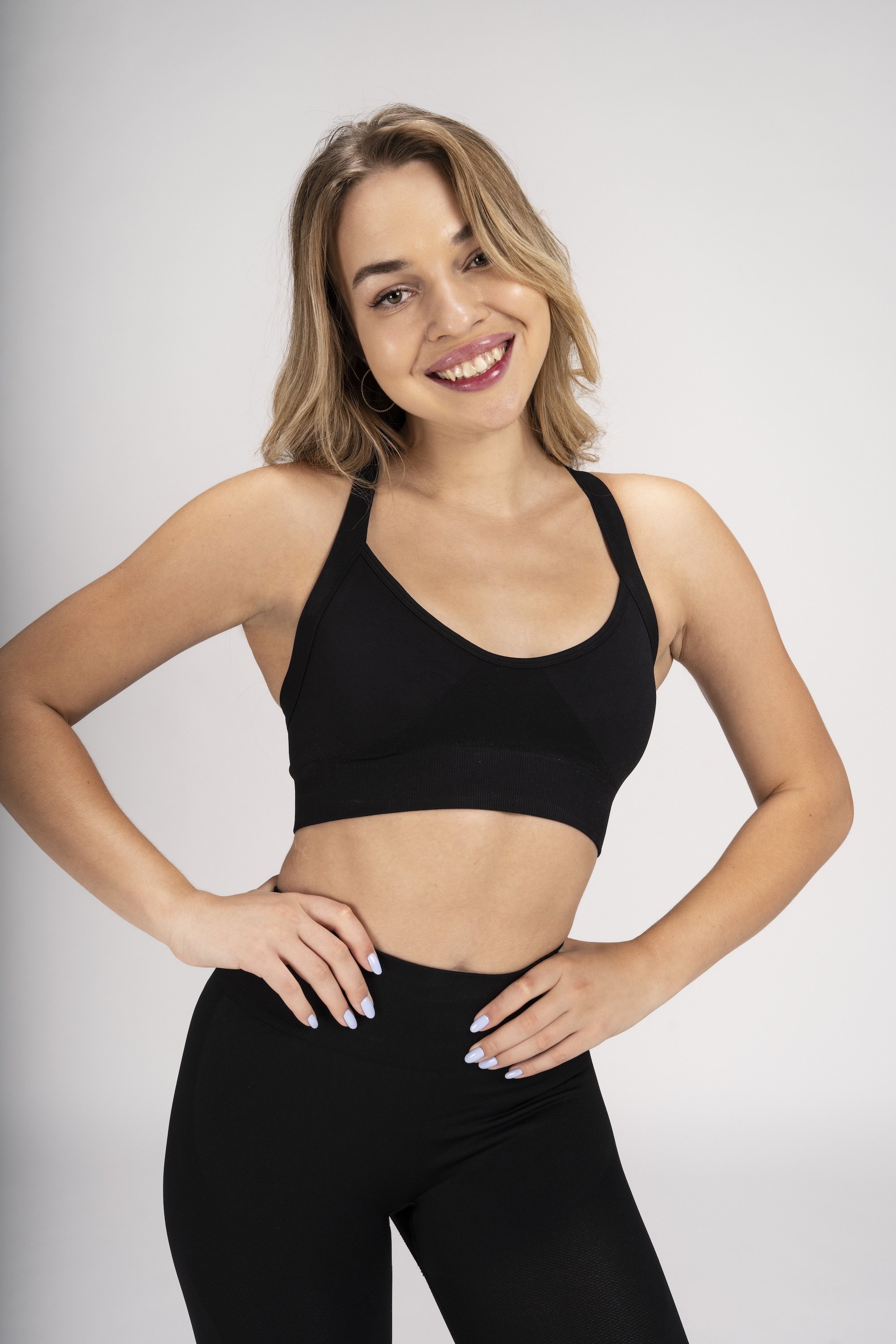 Model wearing a black Annathletics sports bra and leggings against a neutral studio background.