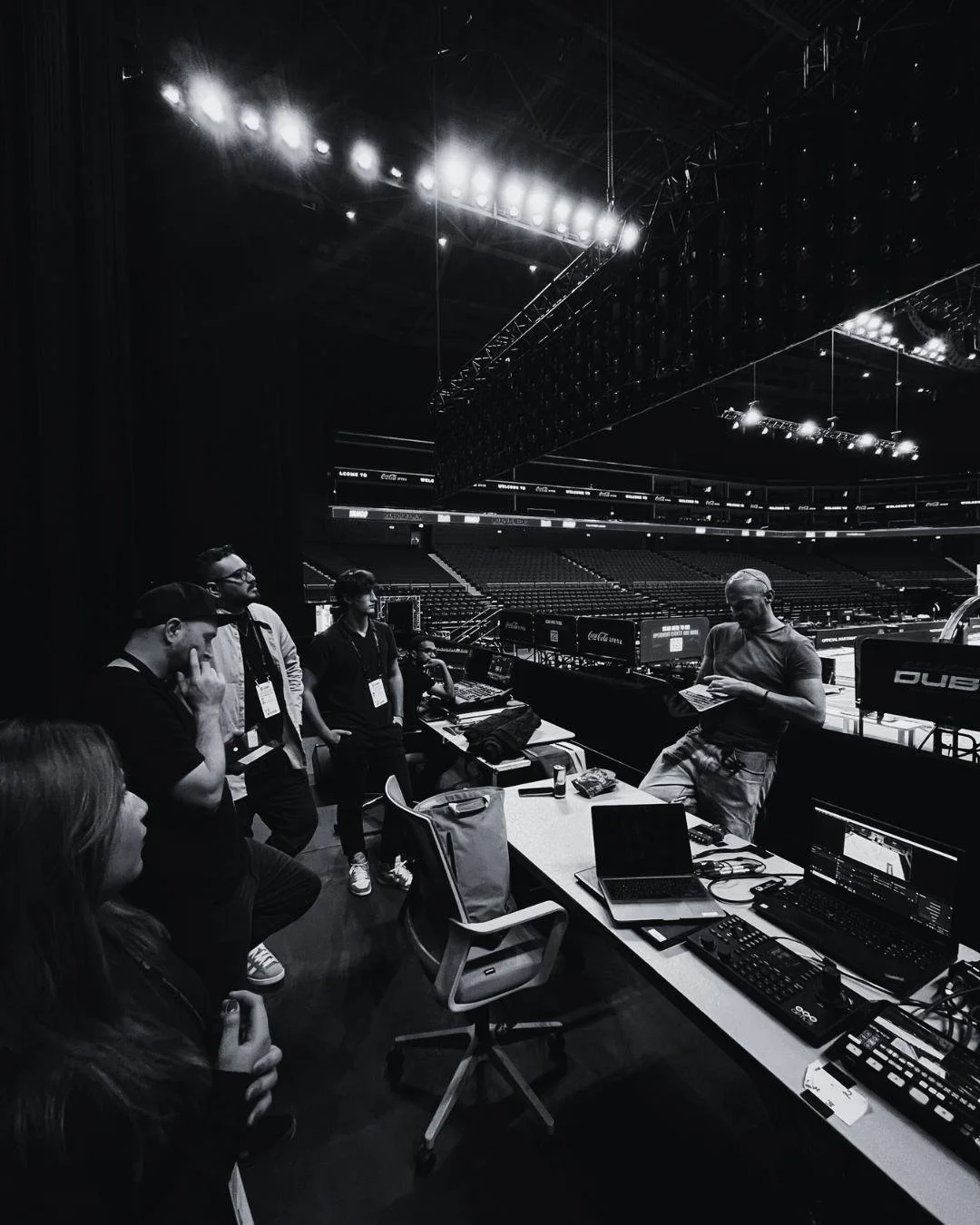 Production team briefing beside the courtside control position before a Dubai Basketball home game at Coca-Cola Arena.