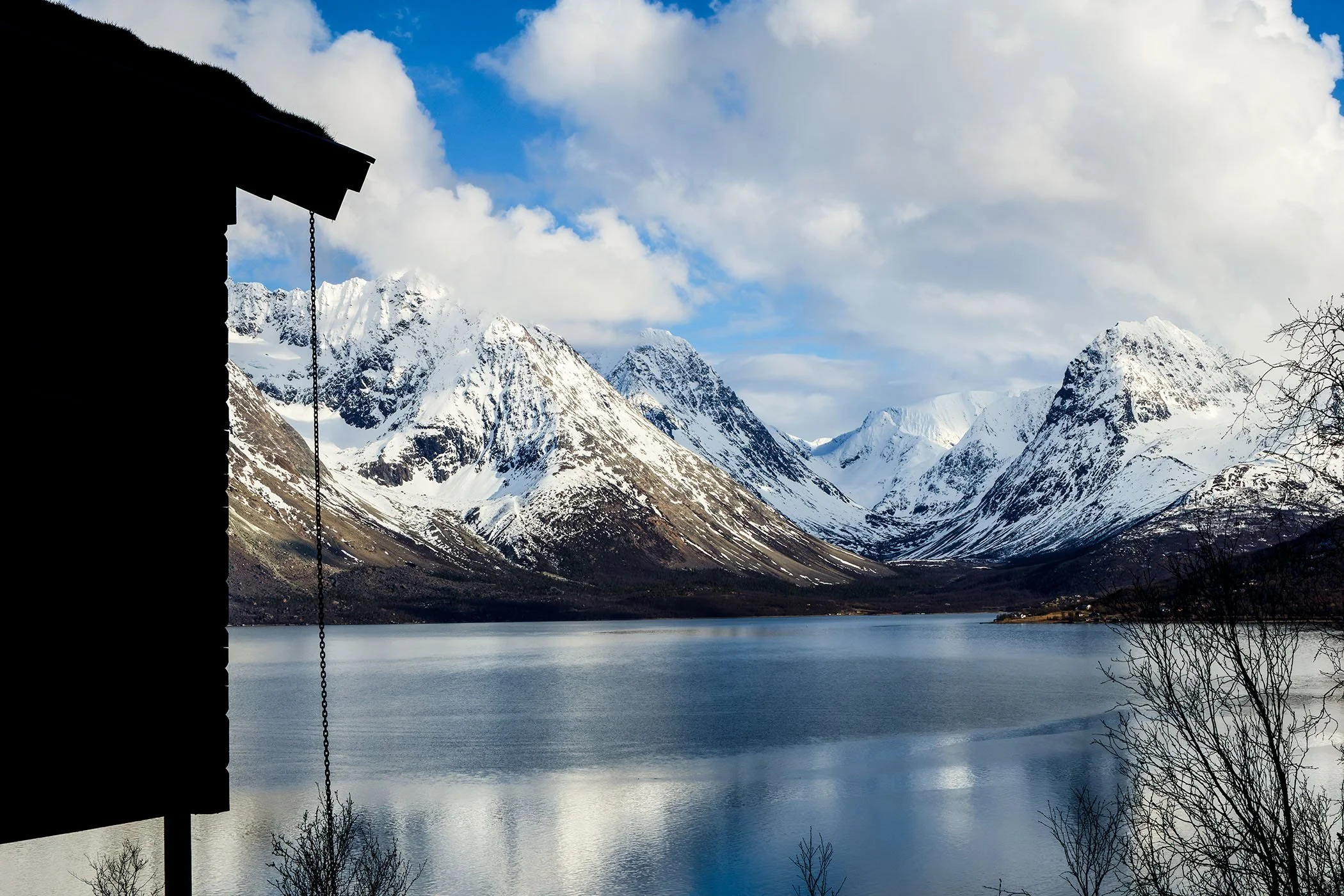 Haus am Ullsfjord vor verschneiten Bergen
