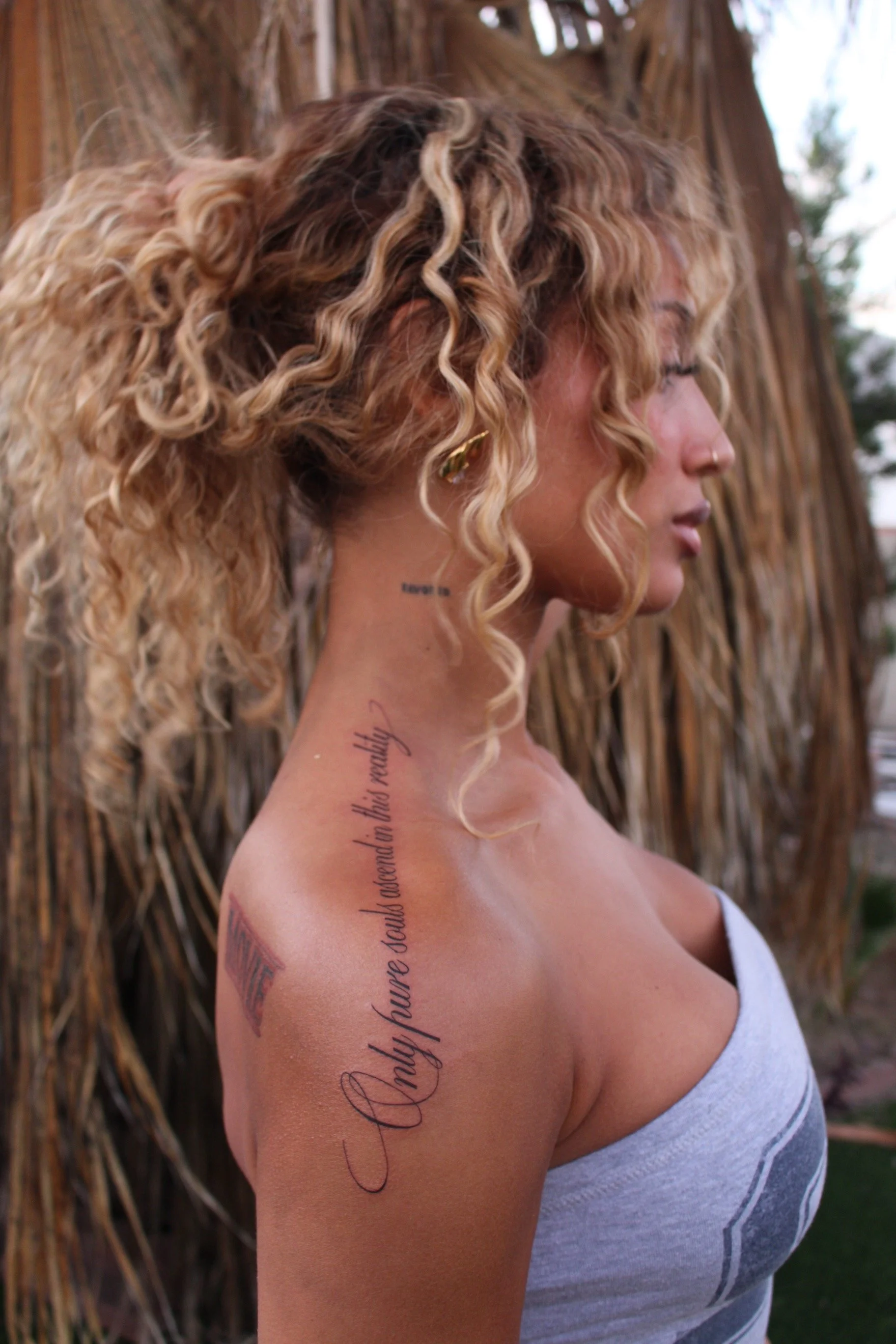 Fine-line script quote tattoo flowing along the shoulder and upper arm, by Bianca Evangeline.