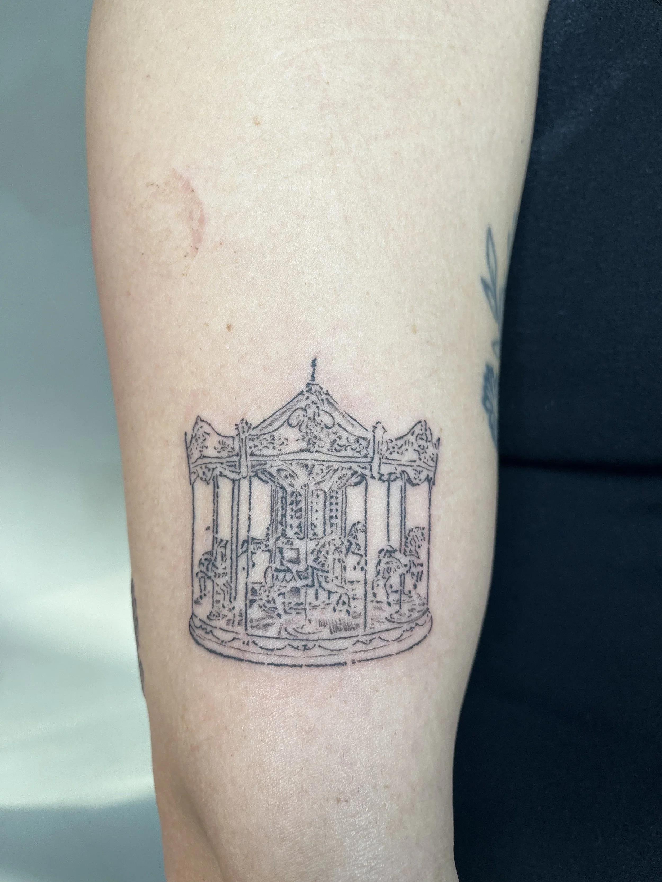 Fine-line ornate carousel tattoo, by Luna Hawke.