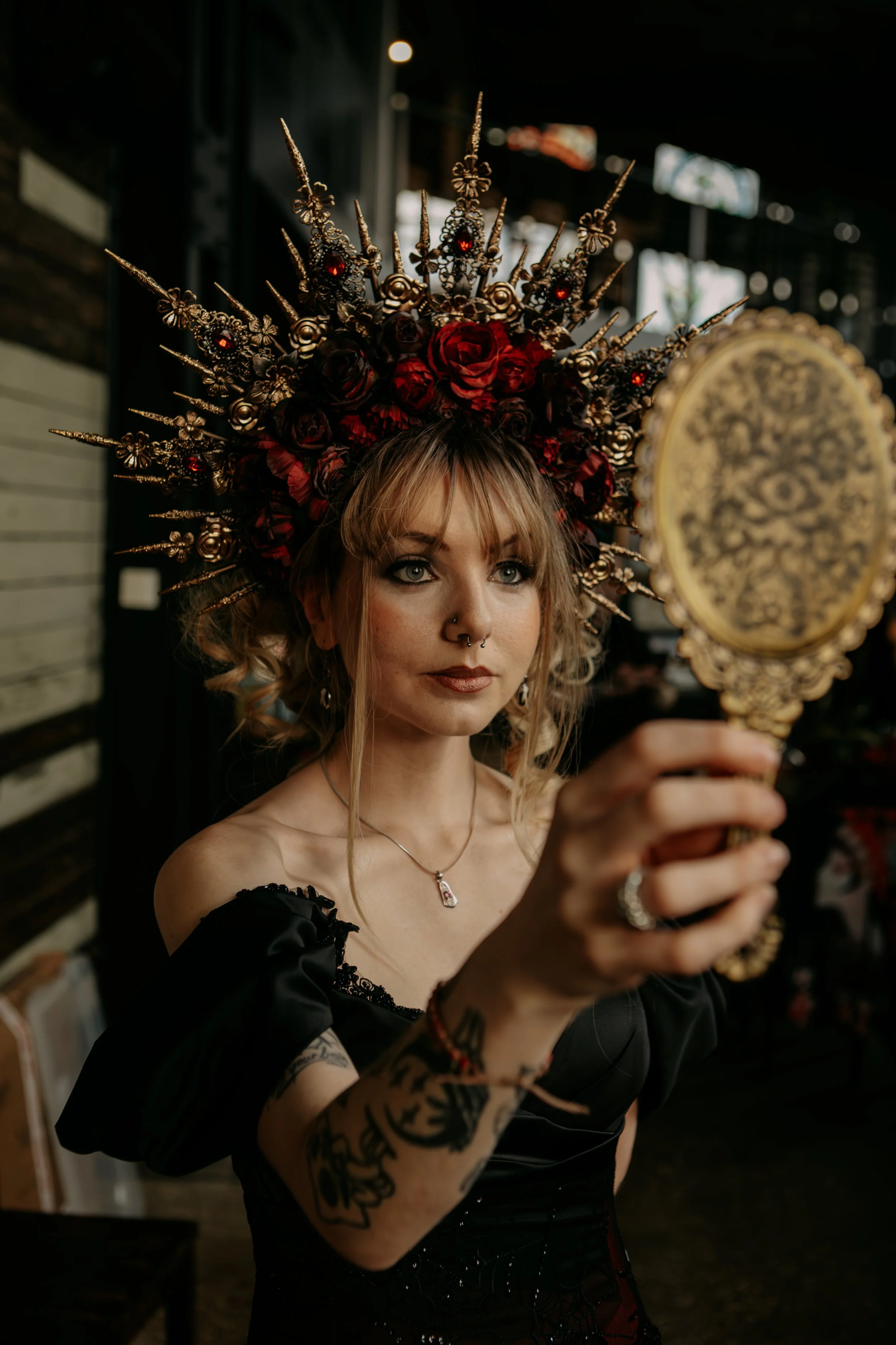 Gothic bridal makeup look featuring a gold and red rose headpiece and vintage handheld mirror