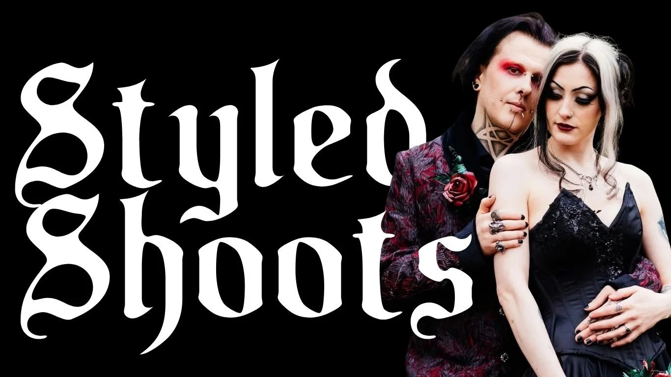 A man and woman with alternative fashion style, the man with black and platinum hair, red makeup, and tattoos, the woman with black and white hair, dark makeup, and goth attire, standing close together in front of a black background with the words 'guilted ghosts' in gothic font.