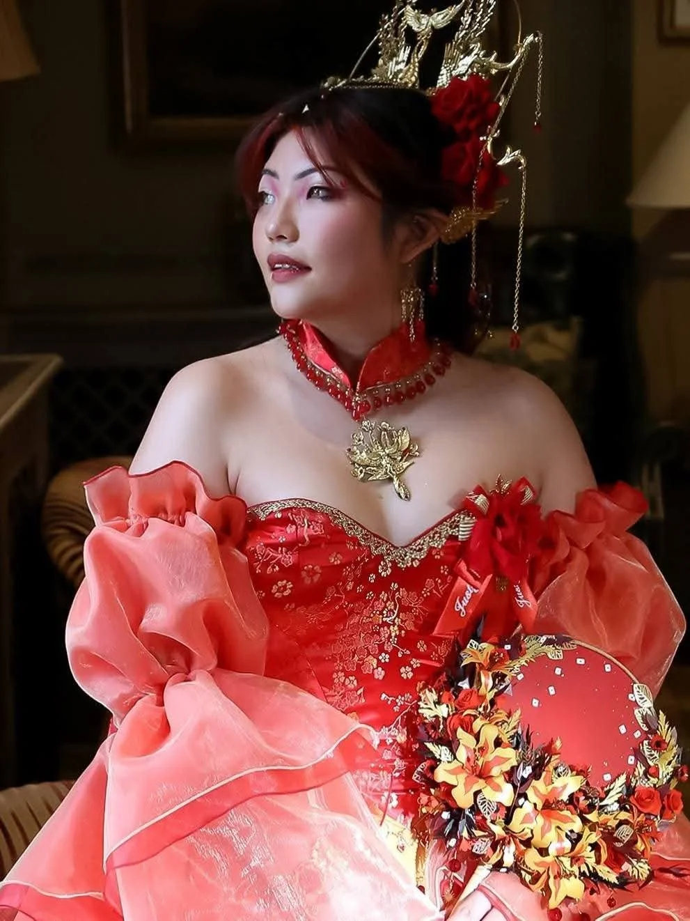 Person wearing a dramatic red wedding dress and ornate floral headpiece — alternative bridal makeup by Sira Rose