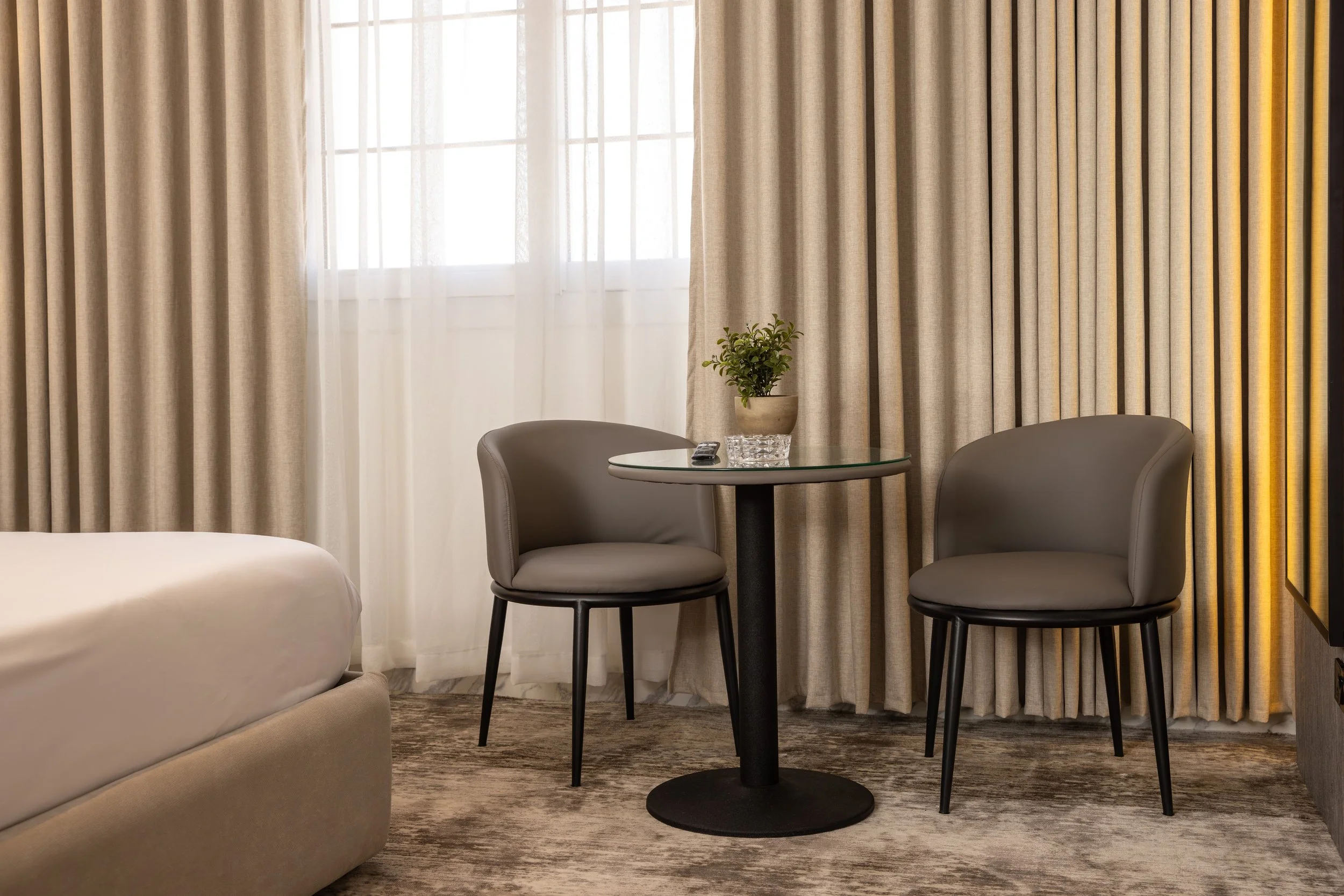 Modern dining room with a round marble table, four upholstered chairs, decorative wall art, and a console table with plants and ornaments.