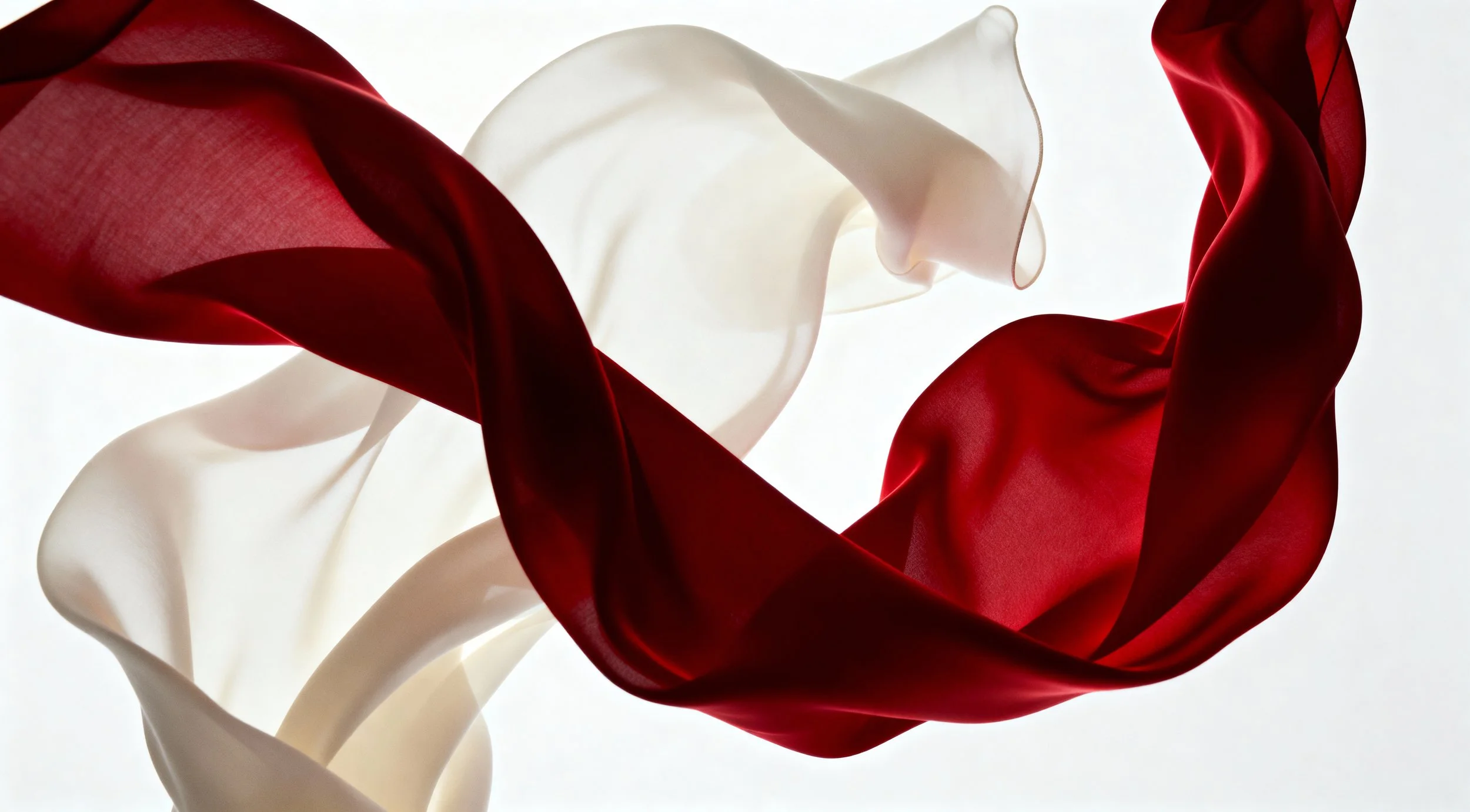 Flowing red and white satin fabric twisting and swirling against a light background.