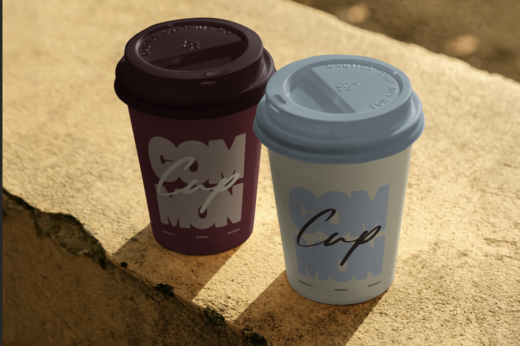 Two disposable coffee cups with plastic lids placed on a stone ledge, one with a maroon lid and the other with a light blue lid, casting shadows in bright sunlight.