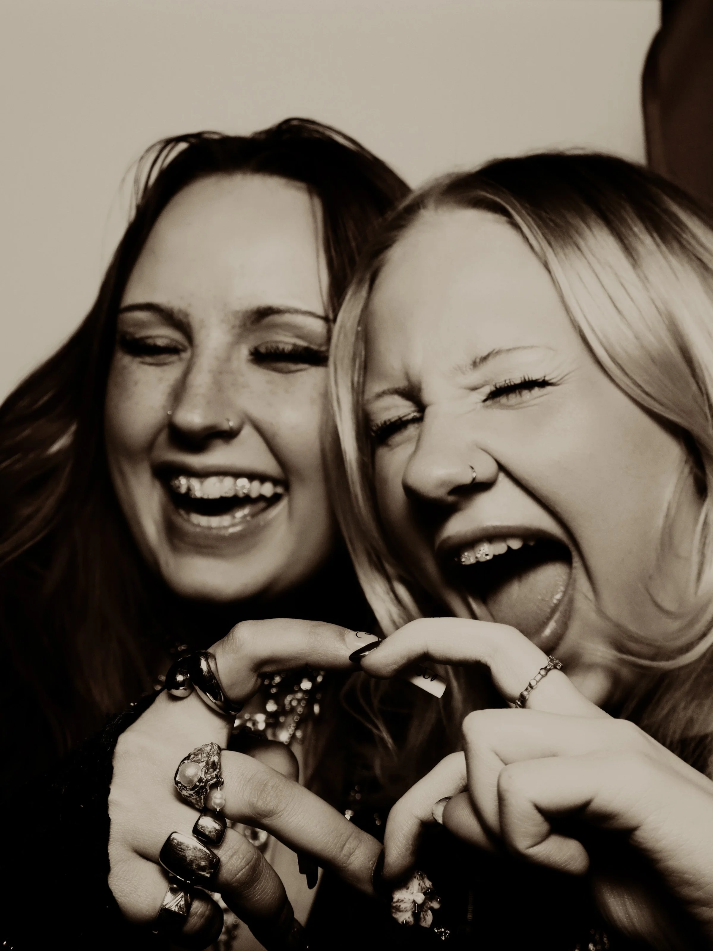 Kaksi naista hymyilee ja tekee sydänsymbolin käsillään.