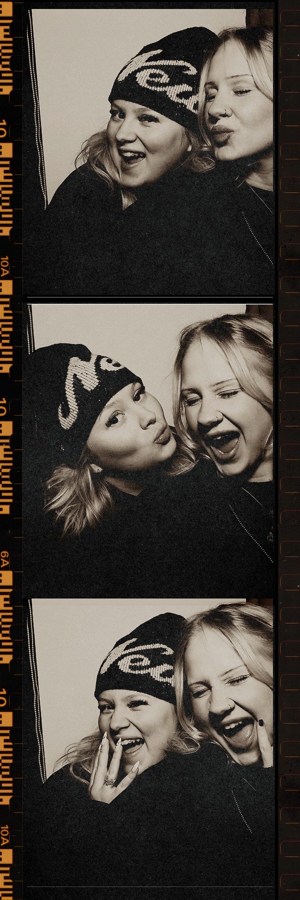 Kaksi nuorta naista hymyilevät ja poseeraavat valokuvakehyksessä, yllään talvivaatteita ja päähineitä.