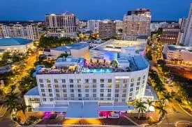 Sarasota Motor Club - premium car service sarasota - Nighttime cityscape with a large modern hotel and surrounding buildings, illuminated with colorful lights.