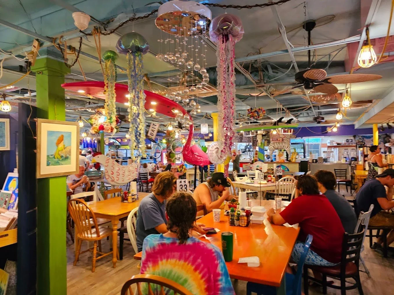 Sarasota Motor Club - Premium Car Service Sarasota - Inside the colorful, eclectic restaurant decorated with hanging tropical umbrellas, flowers, and art, people are sitting at tables enjoying their meals.